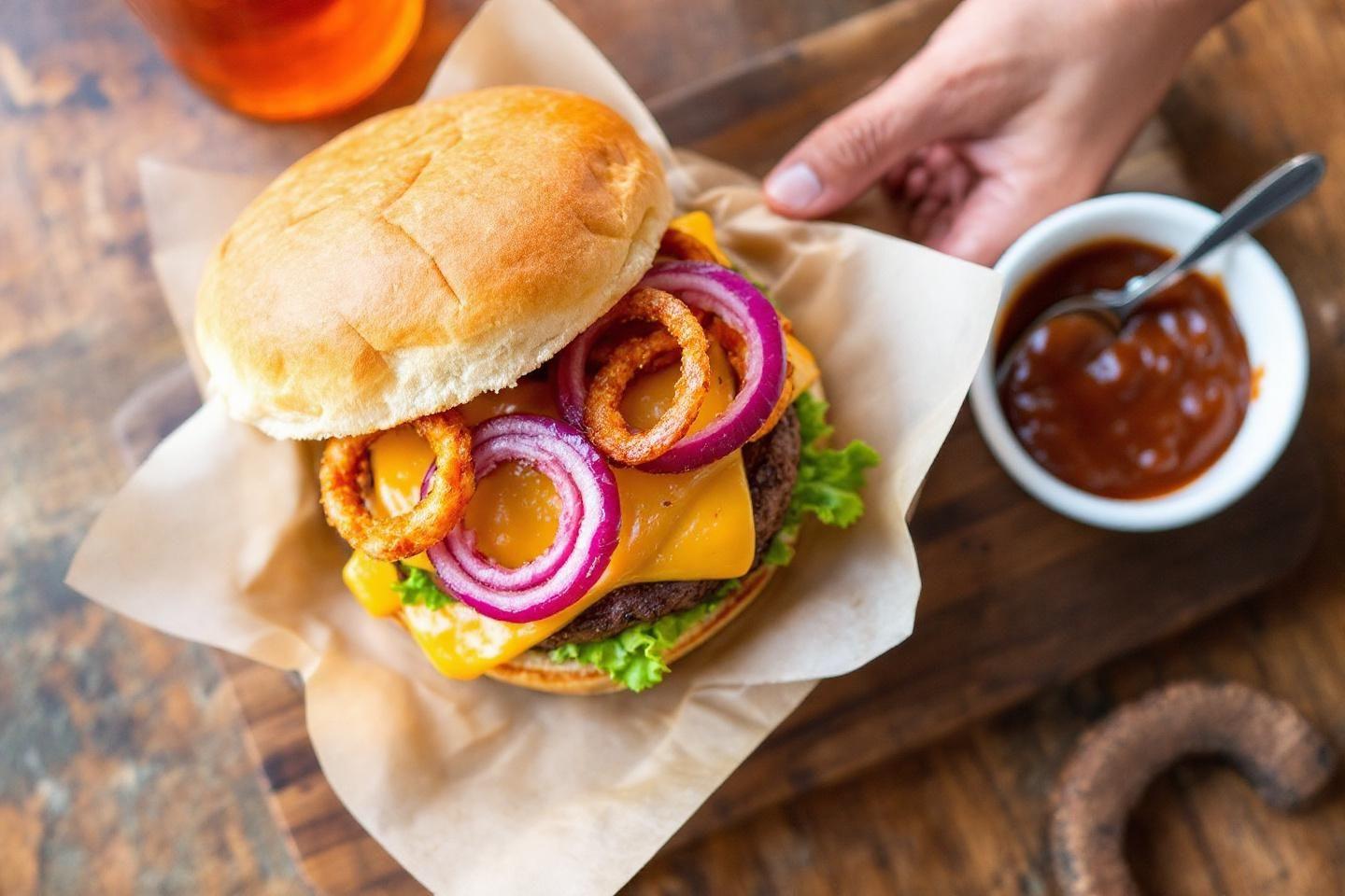 Burger juteux avec fromage, laitue, oignons rouges et frits