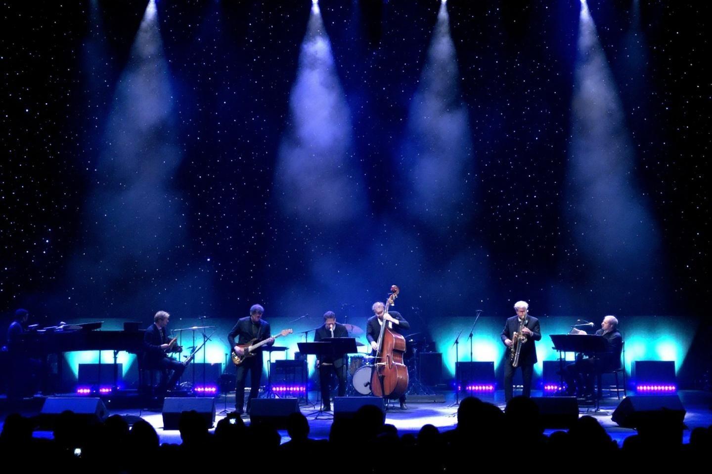 Groupe de musiciens sur sc&egrave;ne avec &eacute;clairage bleu et blanc