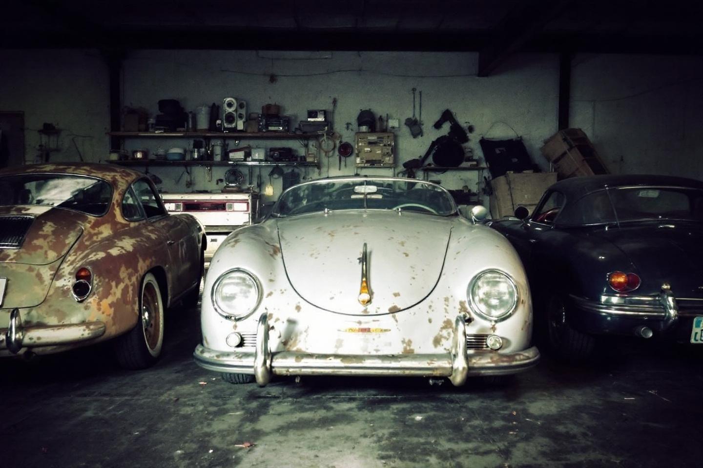 Trois voitures vintage dans un atelier encombr&eacute; et sombre