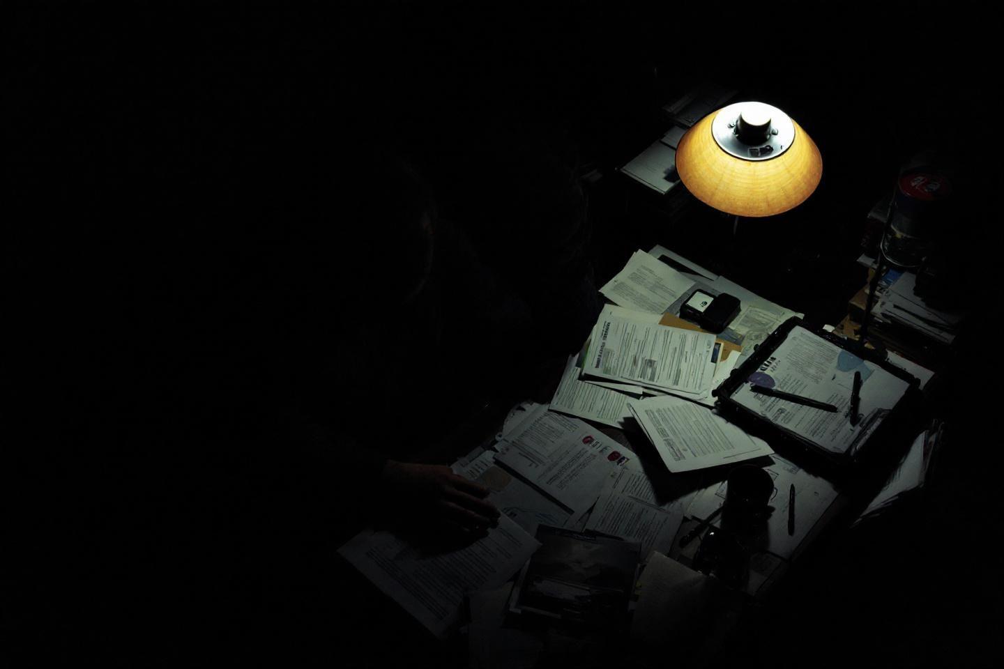 Documents &eacute;parpill&eacute;s sous une lampe jaune dans l'obscurit&eacute;