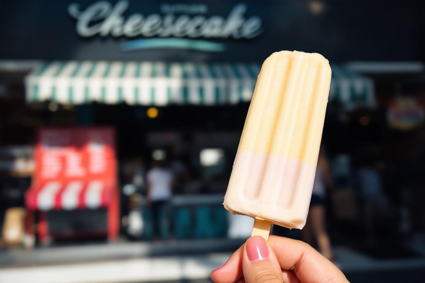 Main tenant une glace à l'eau pâle devant un magasin