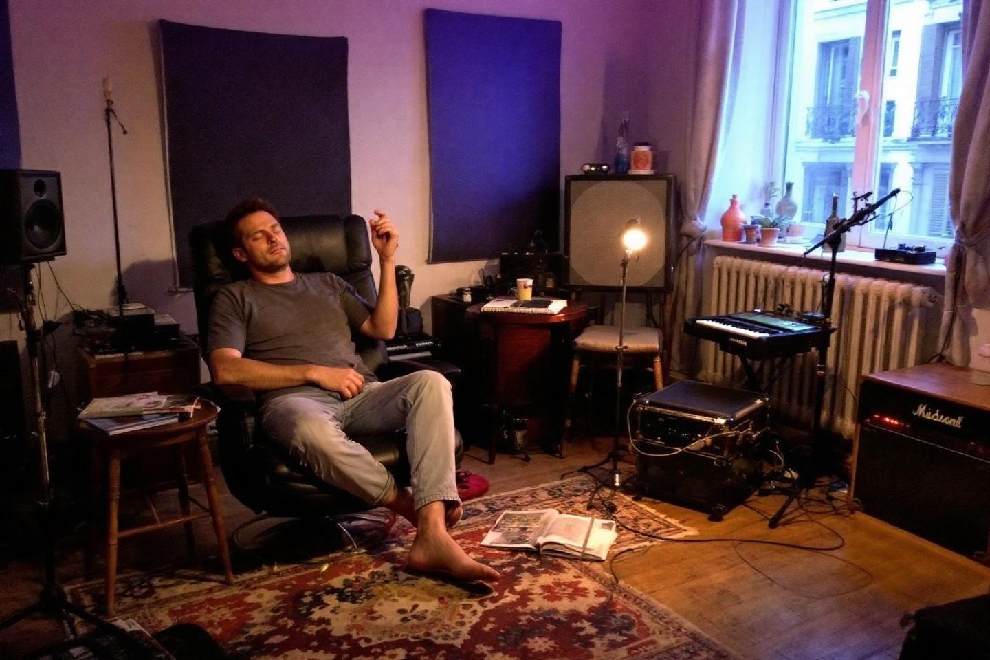 Homme assis dans un studio de musique avec instrument et lumière