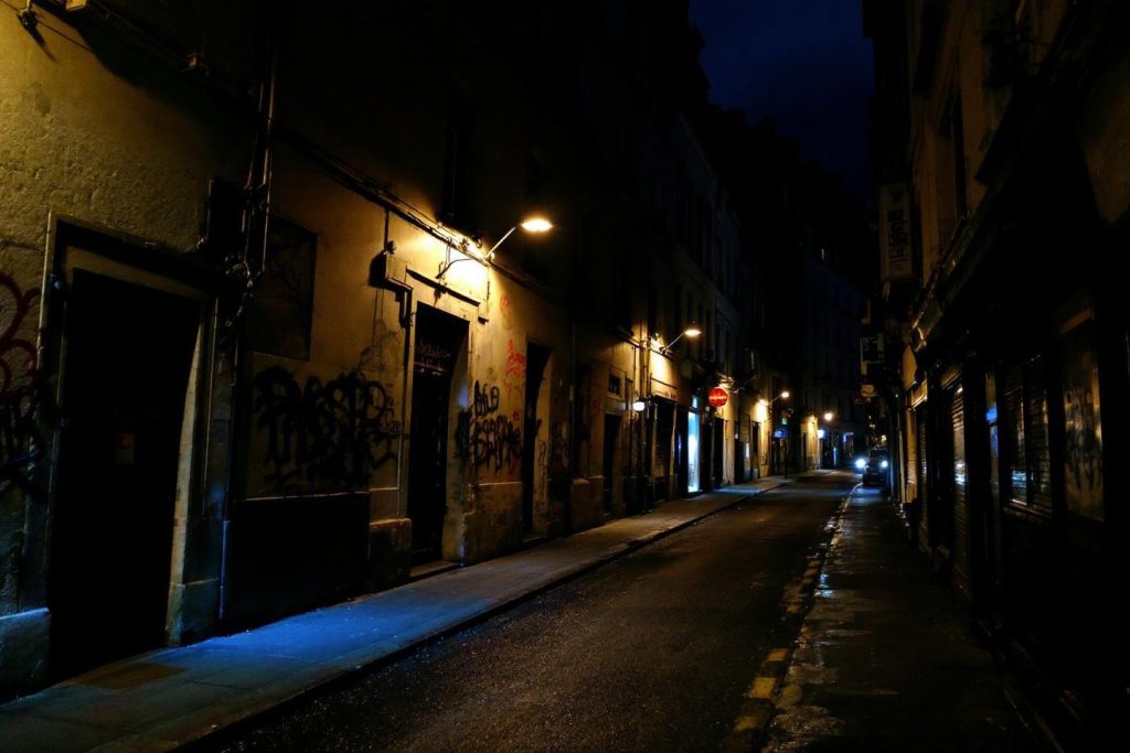 Rue étroite éclairée par des lampadaires avec graffitis