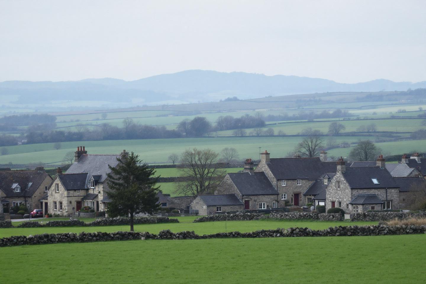 Maisons de pierre grise dans un paysage verdoyant et vallonn&eacute;